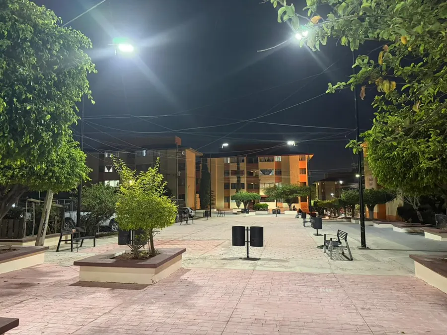 Andador peatonal con luminarias LED entre áreas verdes